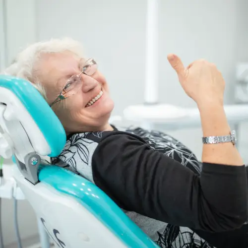 Smiling senior woman in a dental chair giving a thumbs up