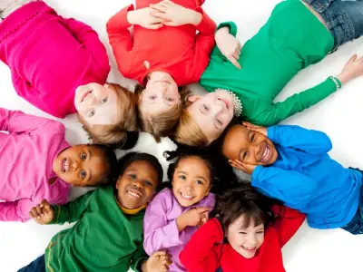 Group of smiling children lying in a circle with their heads together
