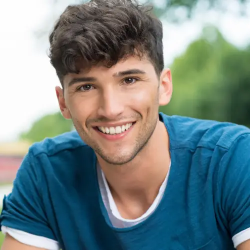 Smiling young man in a blue T-shirt outdoors