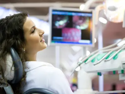 Patient in a dental chair viewing magnified images of her teeth on a monitor