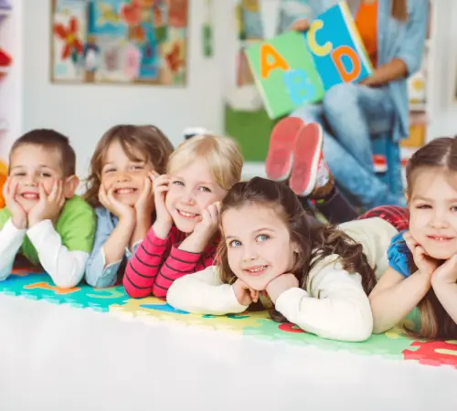 Smiling children lying on a colorful play mat in a classroom