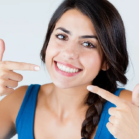 Woman pointing to her bright white smile with both hands