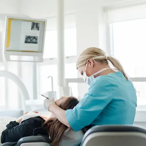 Dentist examining a reclining patient with X-rays displayed on a monitor
