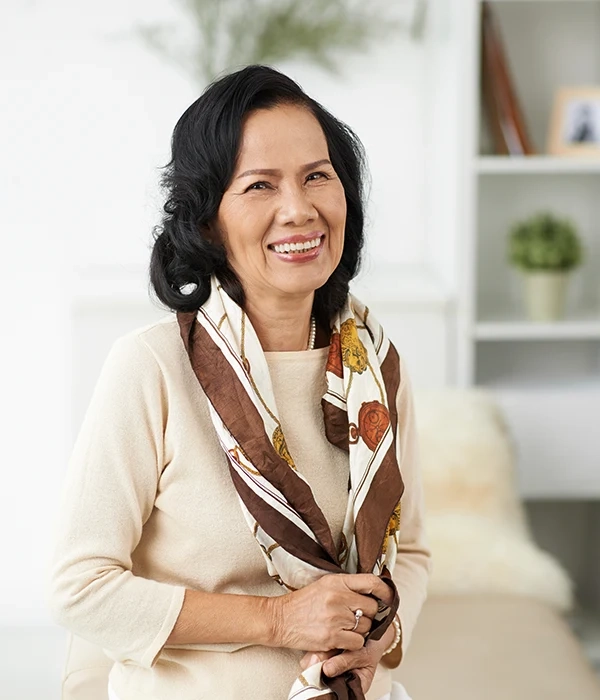 Smiling older woman wearing a patterned scarf at home